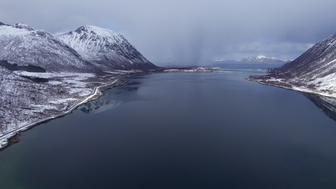 Tempesta di neve che attraversa un fiordo sulle isole Lofoten durante l'inverno ad aprile, ripresa aerea in avanzamento