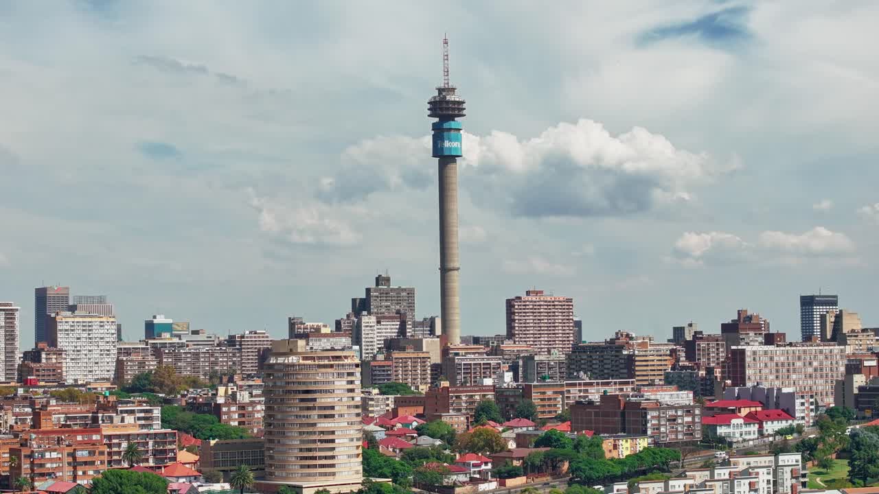 Splendido timelapse aereo in 4K del paesaggio urbano di Johannesburg a mezzogiorno. Alberi verdi, veicoli in movimento e nuvole dinamiche sopra lo skyline della città sudafricana