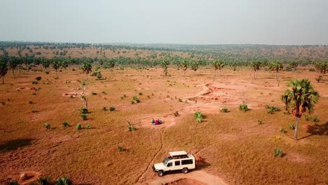 aerial view of people eating in the table with 4x4 vehicle parked in the savannah of africa