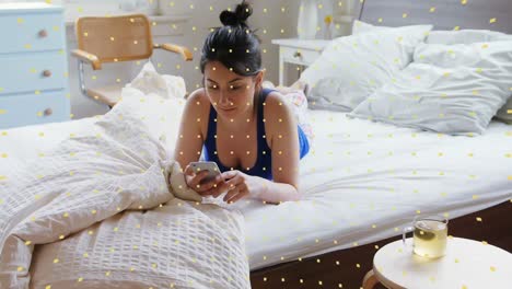 animation of social distancing message over caucasian woman lying on bed using a smartphone