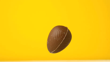 Animación-De-Formas-Caleidoscópicas-Rojas-Sobre-Huevos-De-Pascua-De-Chocolate-Cayendo-Y-Rebotando,-En-Amarillo