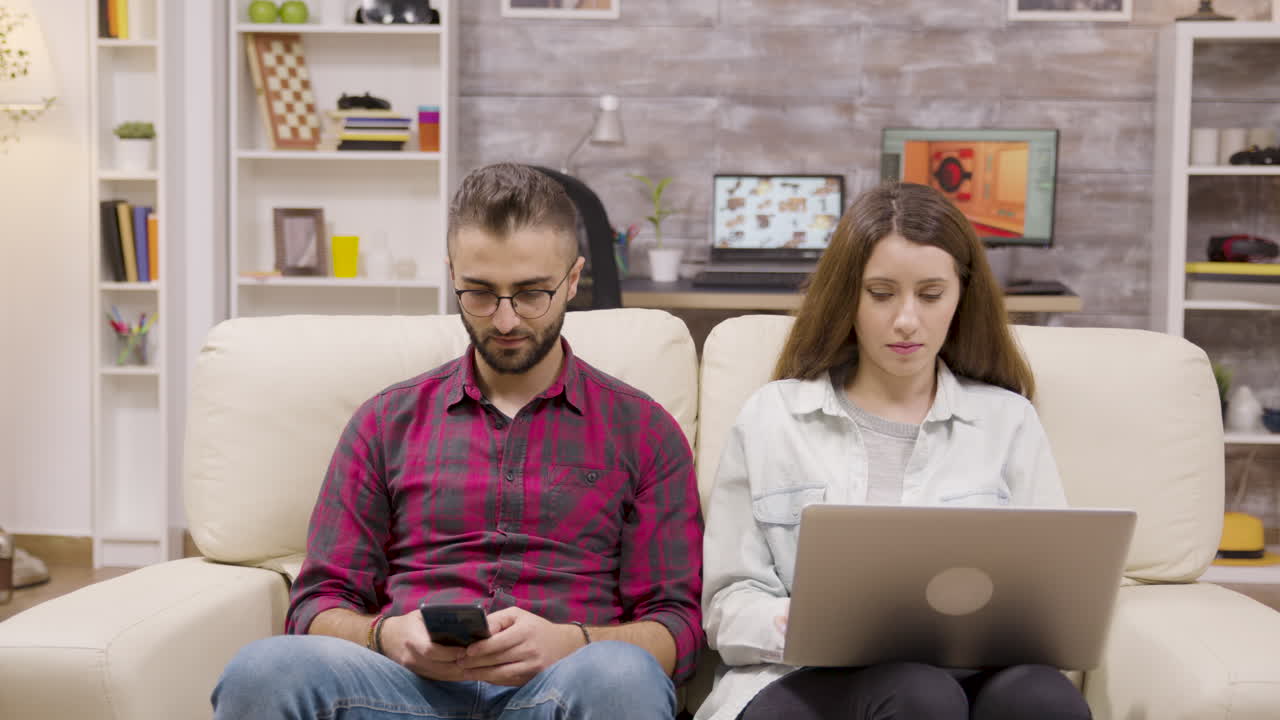 Couple using technology on couch