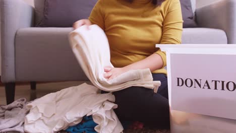 female hands sorting clothes for donation and putting them in a box to take to the distribution center