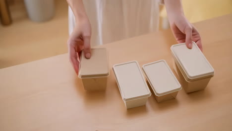 hands arranging meal prep containers on a table