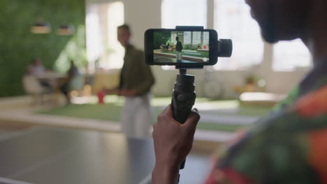 young-black-business-people-playing-ping-pong-in-office-enjoying-competitive-fun-colleague-using-smartphone-sharing-game-on-social-media-taking-video