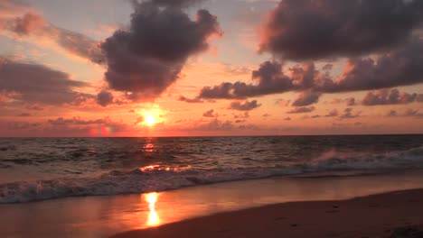 dramatic beach sunrise burning the sky, sun shining in red color during idyllic sea background