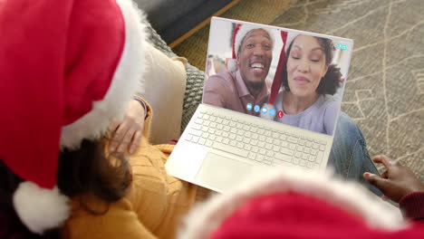 dos parejas felices y diversas teniendo una llamada de video de laptop de navidad, en cámara lenta