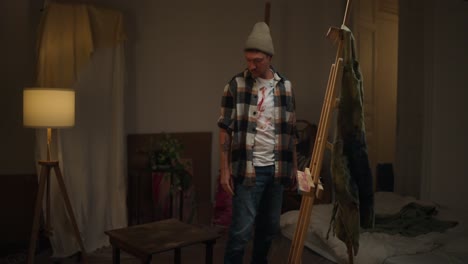 artist working on a painting in their home studio at night