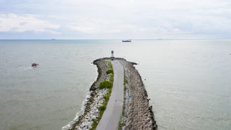 Aerial-view-moving-forward-of-the-lighthouse-above-the-pier-path-of-Farol-Do-Molhe-Da-Barra-De-Itajaí,-Santa-Catarina,-Brazil