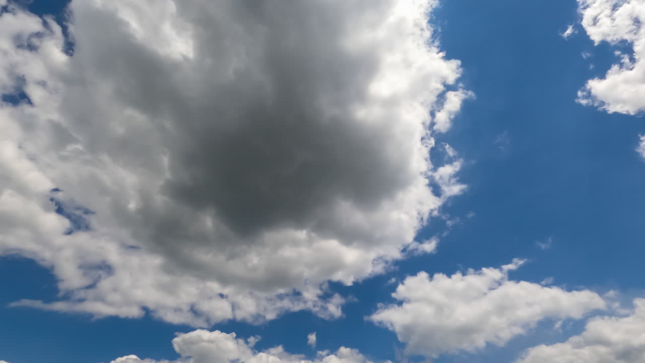 Cloudscape building in the blue sky. Soft puffy clouds flying quickly. Low angle perspective. Timelapse.