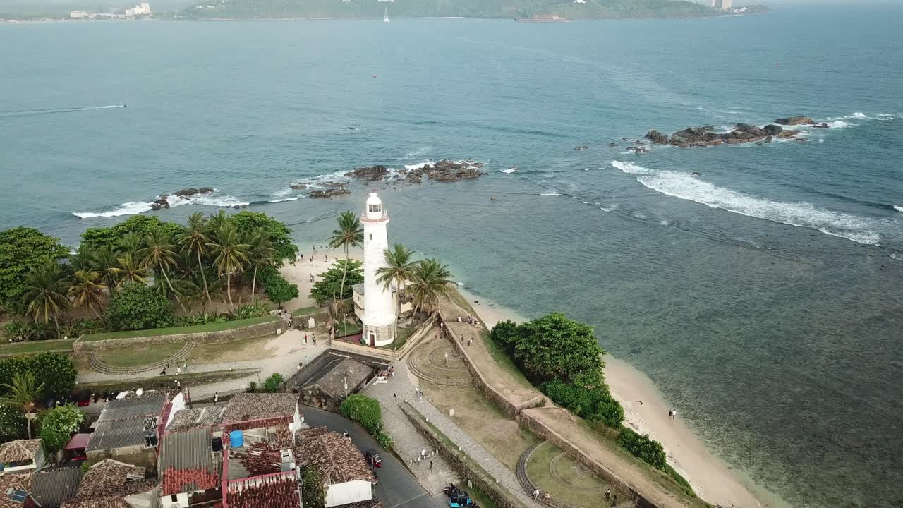 A scenic drone flight along Galle's coastline, capturing the lighthouse standing tall by the ocean. The peaceful beach below offers an escape into tropical paradise.