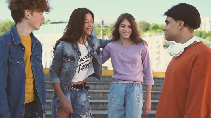 Un grupo de amigos adolescentes, dos chicas y dos chicos, ponen las manos en el centro y chocan.