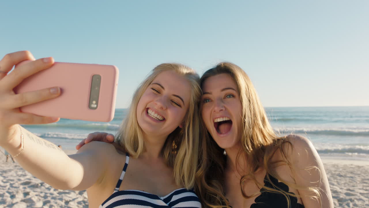 amigas tomando fotos selfie usando teléfonos inteligentes en la playa divirtiéndose compartiendo vacaciones de verano disfrutando del verano junto al mar