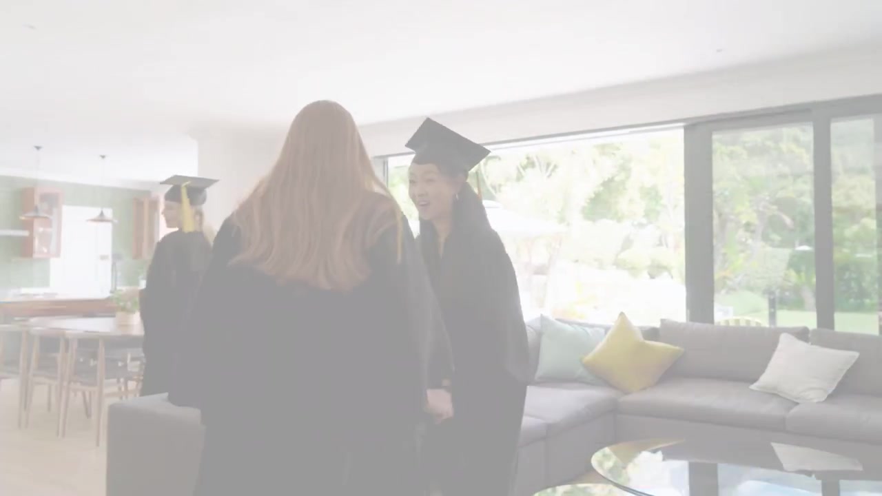 Laureati che entrano attraverso una porta a pannelli, sistemano le toghe sul divano, celebrando l'istruzione e gli amici.