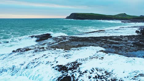 Churning-green-white-seafoam-drains-off-jagged-rocks-on-coastline-of-New-Zealand