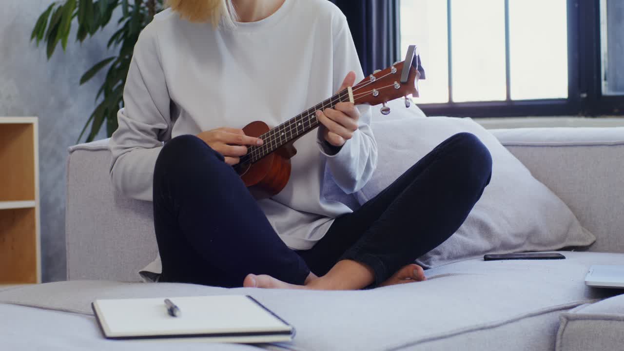 mujer tocando el ukulele en un sofá