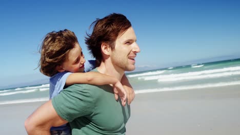 Father-giving-piggyback-to-his-son-at-beach