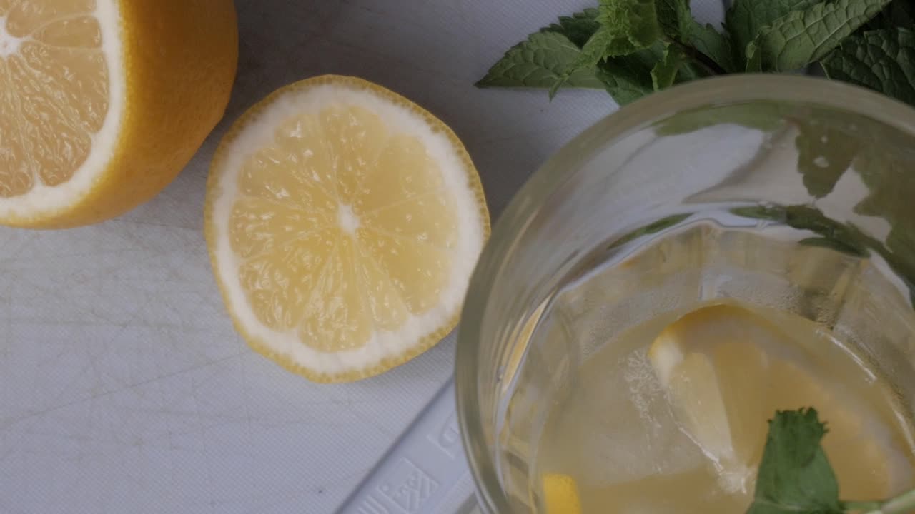 Fresh lemon slices on a cutting board with a glass of lemonade nearby