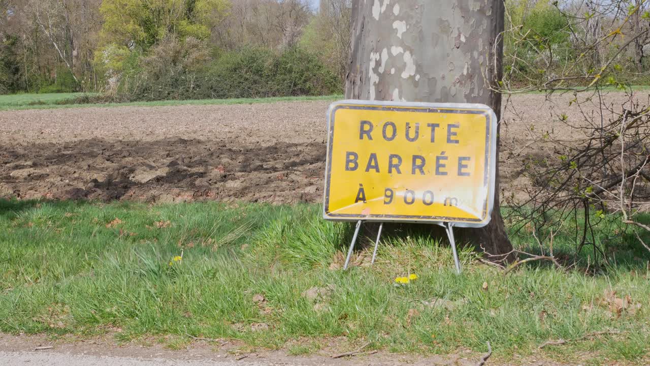 cruce de ciclistas frente a un cartel de "carretera cerrada" en francés