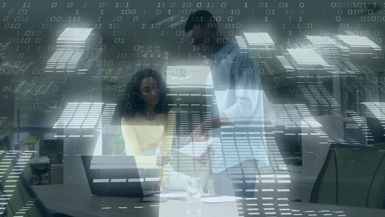 Binary code animation over two people working together at office desk