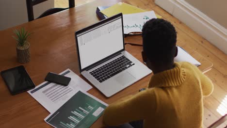 african american man sitting at desk watching coding data processing on laptop screen