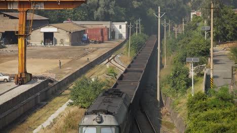 traditional chinese feight train crossing through an industrial city located in the valley of sichuan, china