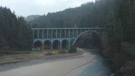 Drone-Vuela-Hacia-Las-Nubes-Sobre-El-Puente-De-Cape-Creek,-En-La-Costa-De-Oregon