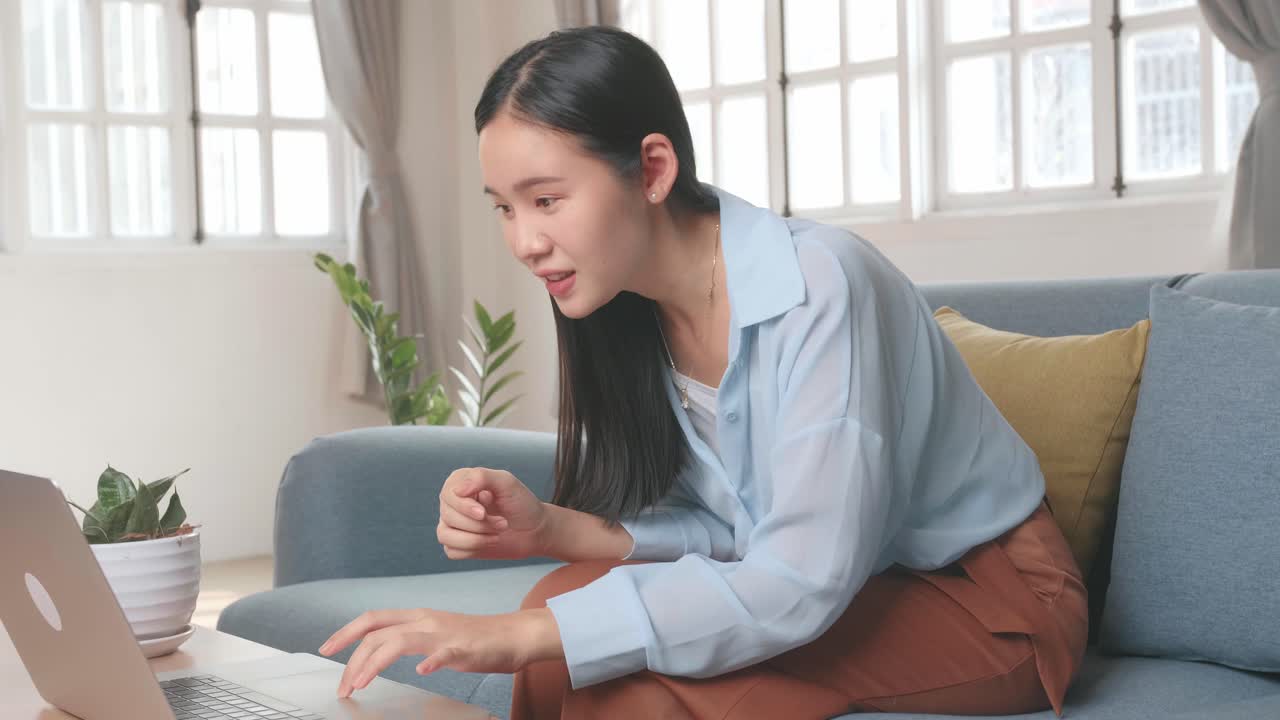 Asian Female Using Laptop And Celebrates In Home Living Room, Video In 4K