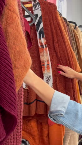 a young woman buys used ecofriendly clothes at a thrift store a young woman looks at used clothes sale shopping fashion and people concept woman chooses clothes in vintage clothing store