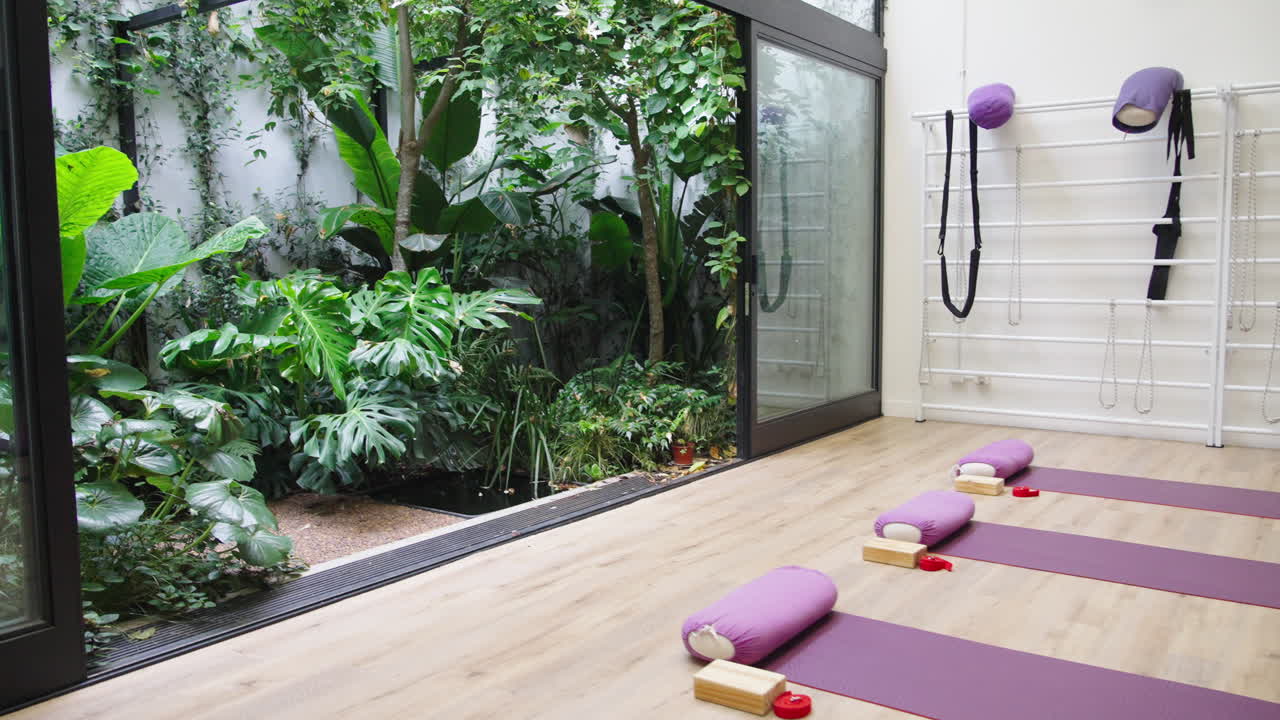 Tomt yogastudio med måtter og bolstere med udsigt til en grøn have