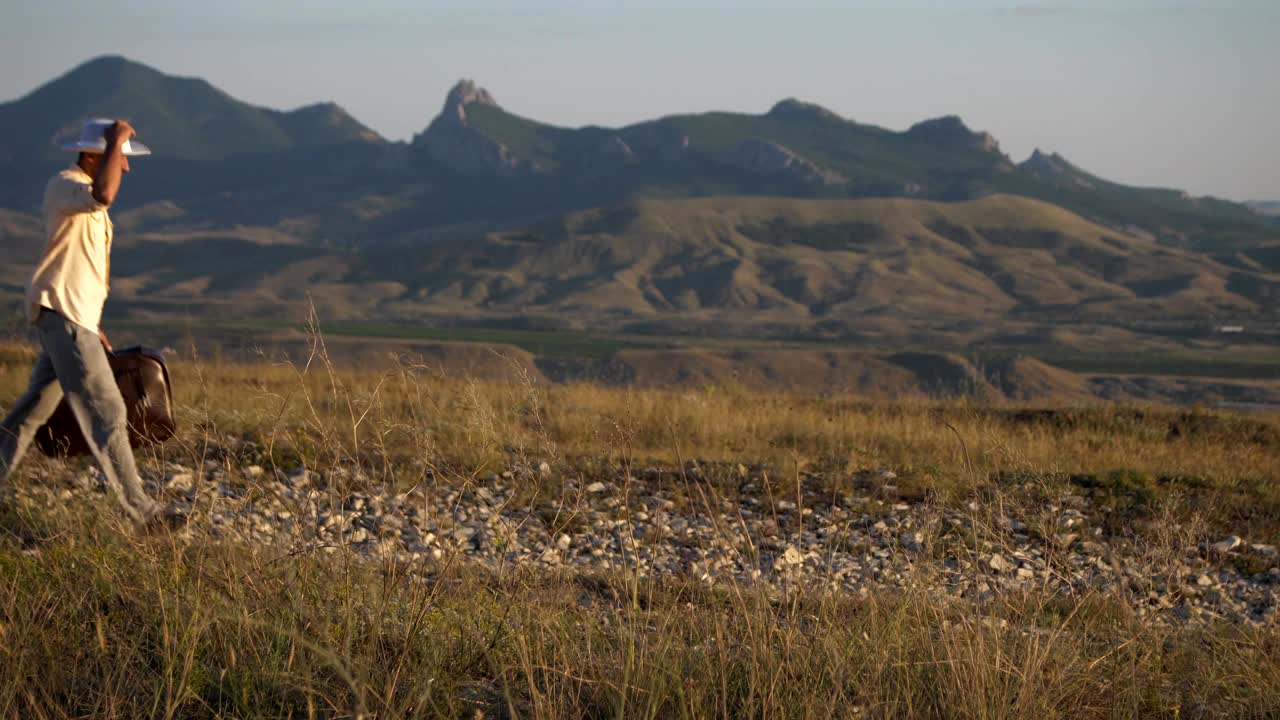 가방을 들고 있는 한 남자가 산의 배경으로 고 있다