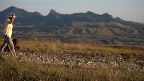 a man with a suitcase walks against the background of the mountains