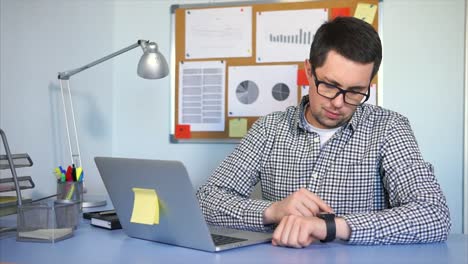 hombre de negocios comprobando su reloj inteligente en la oficina