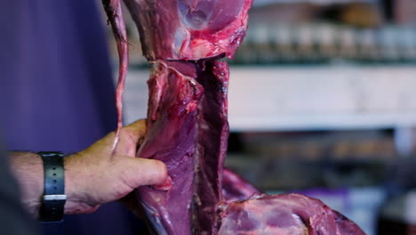el carnicero cortando hábilmente la carne de venado del lomo de la carcasa de la gacela