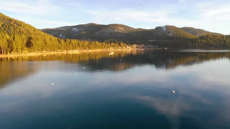 Evening-Sunset-Drone-Aerial-Over-Glenbrook,-Lake-Tahoe,-Nevada,-With-Old-Pier-Pilings-Coming-Out-Of-Calm-Water