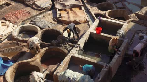 4k footage of traditional moroccans at their work standing in tubs, tanning leather and the dye process in the leather manufacturing area of marrakesh with shops of  merchants in the narrow streets.