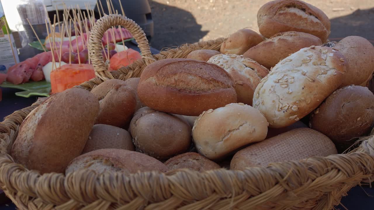 Artisan bread rolls displaying golden brown crusts and soft interiors, nestled in rustic wicker basket, representing variety of freshly baked gourmet bread selections