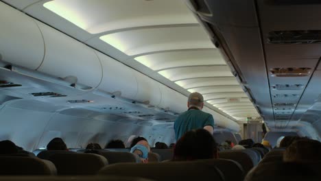 man walking down the isle on an airbus airliner cabin in flight - back view