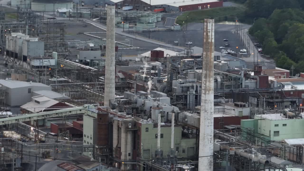 Industrial plant with tall chimneys, pipes, and metal structures, a dense network of machinery and buildings, showing the raw, powerful side of heavy industry in America
