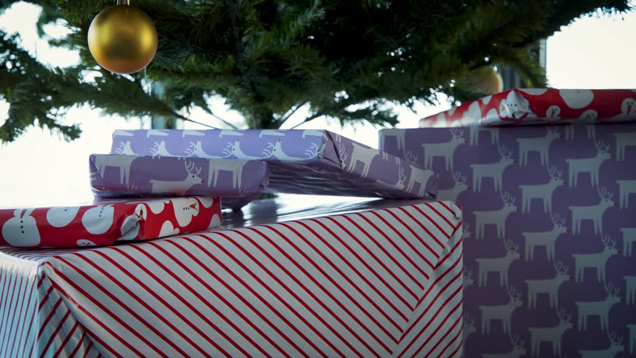 Regali ben impacchettati con carta natalizia sotto un albero artificiale