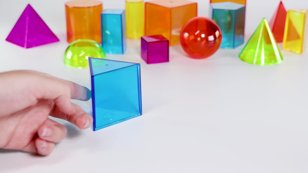 Hands interact with vibrant geometric shapes on a white background, demonstrating movement and arrangement in bright lighting