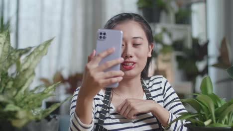 close up of asian woman waving hands and talking while live stream selling plants by smartphone at home