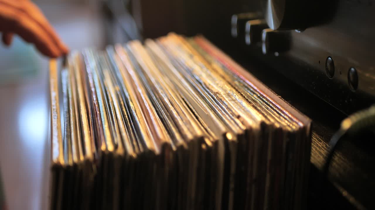 cerrar las manos del hombre hojeando discos de vinilo antiguos en casa