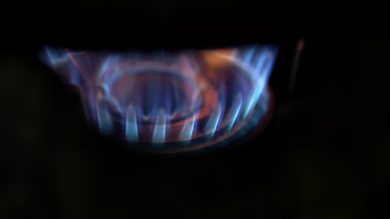Slow-motion capture of intense blue and yellow gas flames with high heat during cooking, highlighting the energy and temperature dynamics in culinary preparation.
