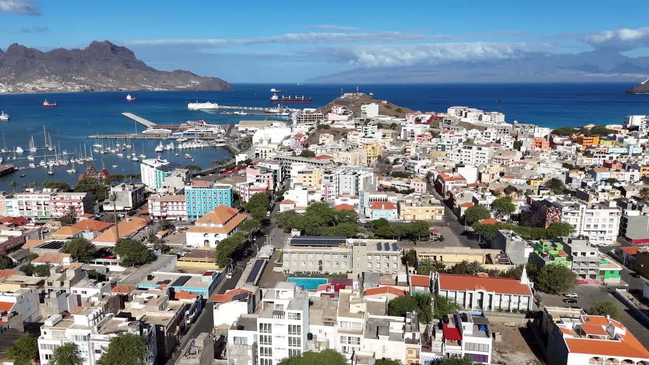 Ampia veduta aerea dello skyline urbano del porto e della città di Mindelo, Sao Vicente. Cattura l'attività marittima, la baia e l'espansione colorata della città sotto il sole splendente di Capo Verde.