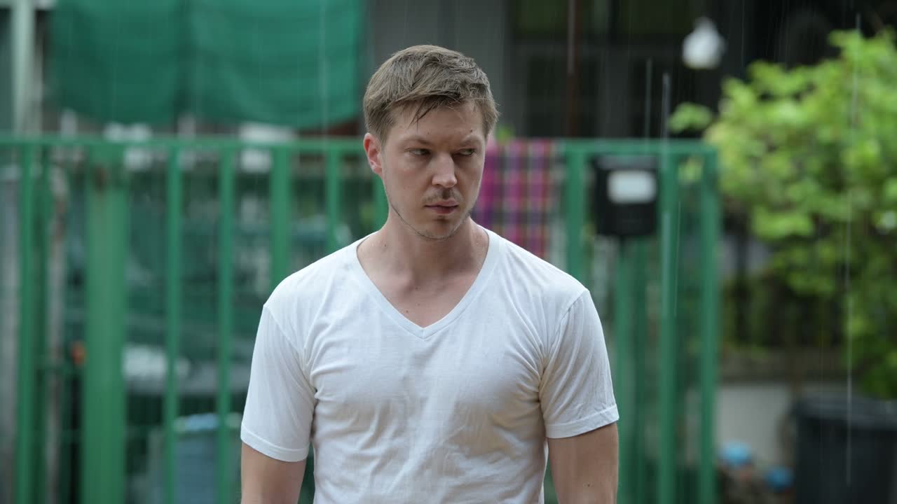 야외에서 비가 오는 동안 혼자 있는 슬픈 젊은 남자