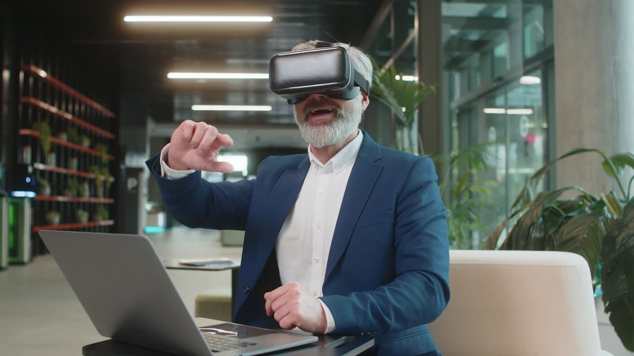 Mature businessman software developer using headset app making presentation in modern office lobby