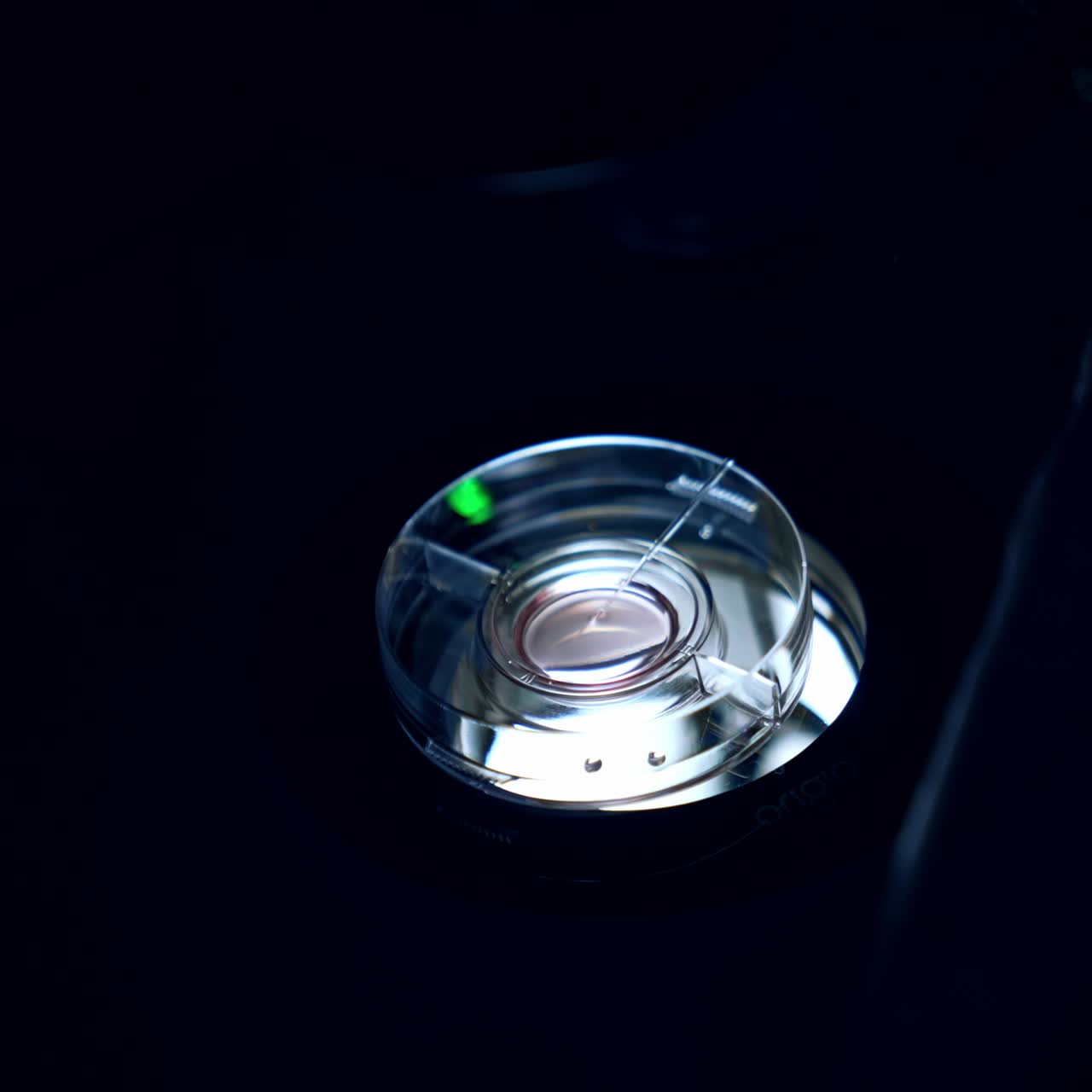 Embryo transfer in the hospital of reproductive health. Petri dish with long pipette in under the microscope in dark room