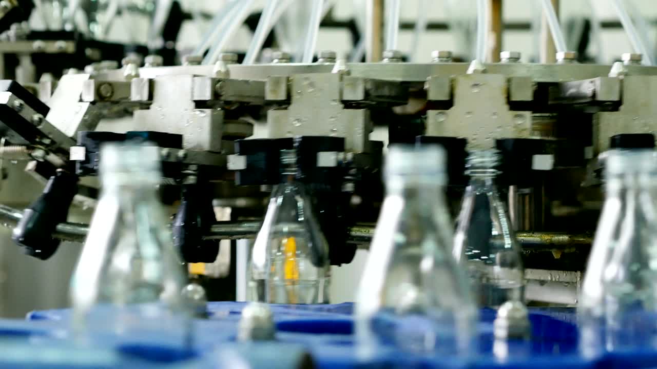 Automatic machine line for filling water in a glass bottle. Bottling of herbal drink in glass bottles. Production of drinking water and beverages.