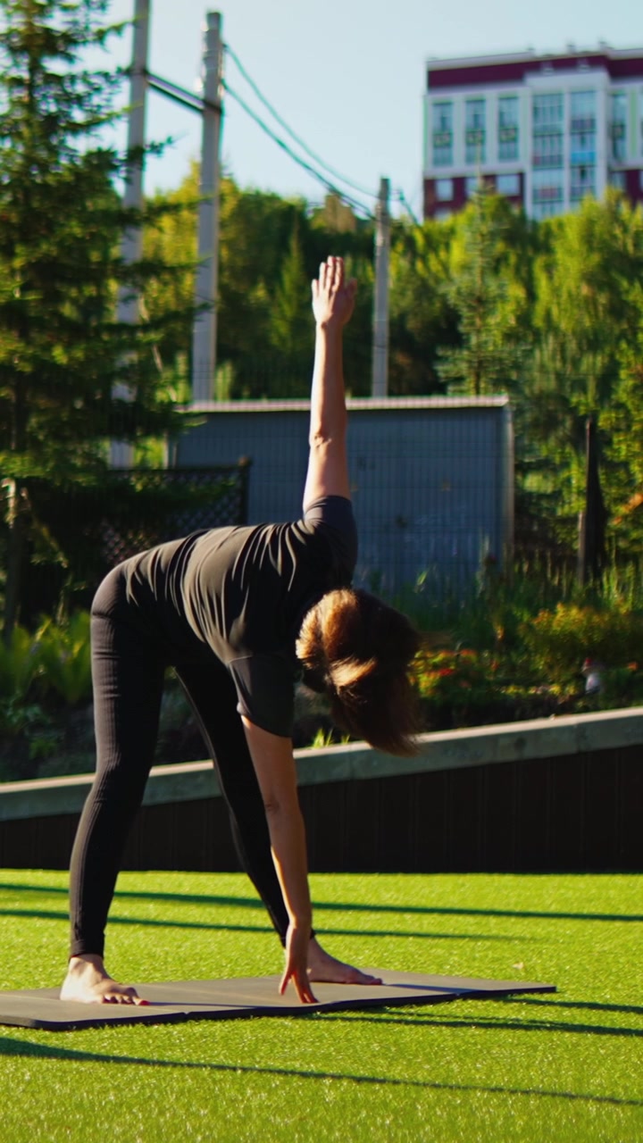 Mujer practicando la postura del triángulo de yoga en una esterilla al aire libre